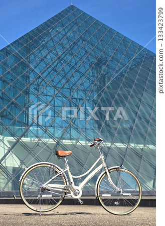 Stylish bicycle parked in front of a modern glass pyramid building on a sunny day Stylish bicycle parked in front of a modern glass pyramid building on a sunny day 133423799