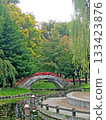 Scenic Japanese garden with a red bridge over a tranquil stream 133423876