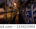 Urban night scene with graffiti art along a canal walkway, illuminated by streetlights 133423904