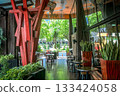 Modern cafe interior with wooden beams, tables, and lush greenery 133424058