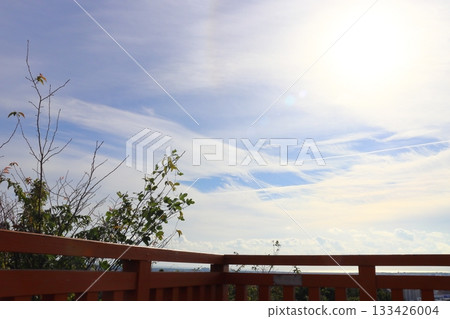 View from the observation deck: fence, cloudy sky, sun View from the observation deck: fence, cloudy sky, sun 133426004