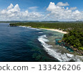 Shoreline with sandy beach, rocky edges, and tropical forest meeting the ocean waves. Siargao, Philippines. Magpupungko Tidal Pool. 133426206