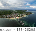Town with coastal shoreline pier sandy beach and boats anchored near clear turquoise water. General Luna, Siargao, Philippines. 133426208