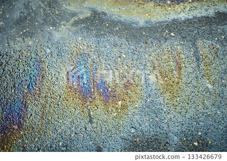 Oil slick on asphalt pavement surface forming colorful iridescent pattern and pollution puddle. Oil slick on asphalt pavement surface forming colorful iridescent pattern and pollution puddle. 133426679