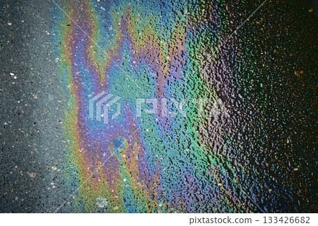 Oil spill forming iridescent rainbow colors and a textured pattern on a wet asphalt surface Oil spill forming iridescent rainbow colors and a textured pattern on a wet asphalt surface 133426682
