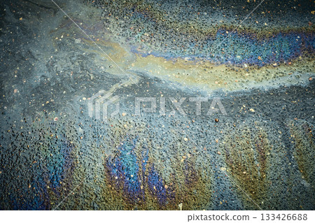 Oil Slick Reflects Colors on Wet Pavement After Rain in Urban Setting During a Cloudy Afternoon. Oil Slick Reflects Colors on Wet Pavement After Rain in Urban Setting During a Cloudy Afternoon. 133426688