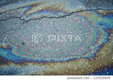 Colorful Oil Spill Creates Vibrant Patterns on Cracked Asphalt Surface in a City Location 133426689