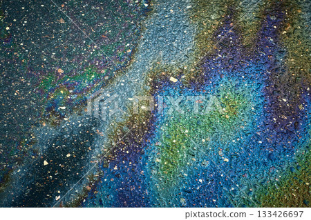 Oil slick on wet asphalt creating a vibrant, abstract rainbow pattern. 133426697