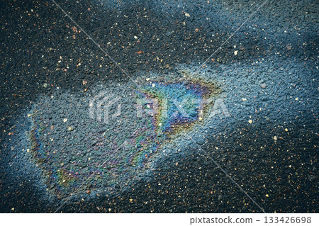 Oil slick creating an iridescent rainbow pattern on wet asphalt pavement, indicating pollution Oil slick creating an iridescent rainbow pattern on wet asphalt pavement, indicating pollution 133426698