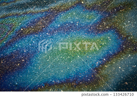 Oil slick on asphalt creating colorful iridescent patterns, symbolizing pollution and environmental impact Oil slick on asphalt creating colorful iridescent patterns, symbolizing pollution and environmental impact 133426710