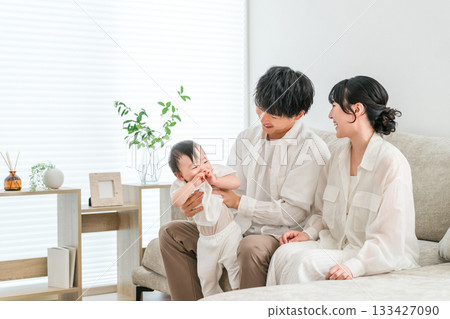 一個年輕的家庭在自家客廳和他們的寶寶共度時光。 一個年輕的家庭在自家客廳和他們的寶寶共度時光。 133427090