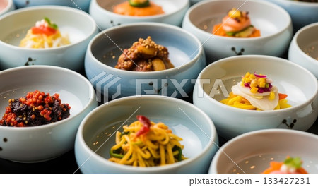Traditional Korean banchan side dishes served in small white ceramic bowls with cute face designs featuring kimchi pickled vegetables and seasoned bean sprouts 133427231