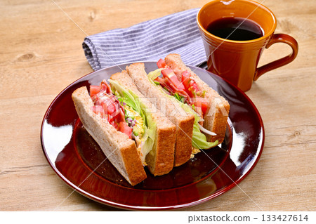 Sandwich and coffee. BLT sandwich, tomato, lettuce, egg mayonnaise, avocado, bacon, purple onion 133427614