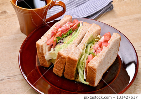 Sandwich and coffee. BLT sandwich, tomato, lettuce, egg mayonnaise, avocado, bacon, purple onion 133427617