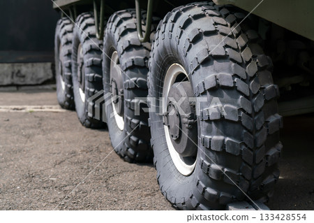 Four large black wheels of an armored vehicle with increased cross-country ability. Four large black wheels of an armored vehicle with increased cross-country ability. 133428554
