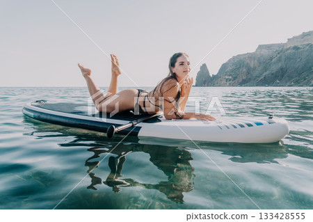 Woman, Paddleboard, Ocean: A woman in a bikini lies on a paddleboard in the ocean on a sunny day. 133428555