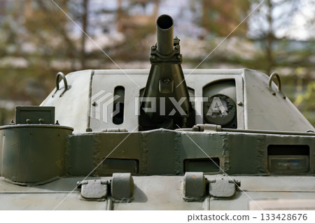 A green tank turret with a gun against the backdrop of a city. A green tank turret with a gun against the backdrop of a city. 133428676