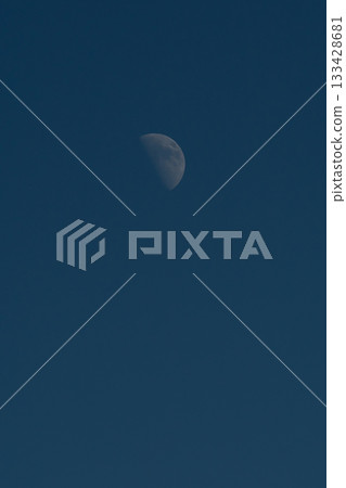 A crescent moon against a dark blue sky. 133428681