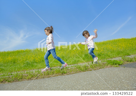 兩姊妹在長廊上玩耍，周圍環繞著油菜花。 133429522
