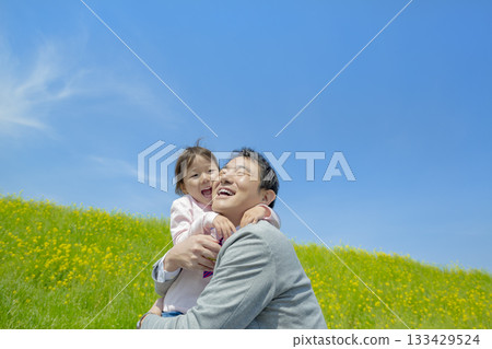 一對父女在長廊上玩耍，周圍環繞著油菜花。 133429524
