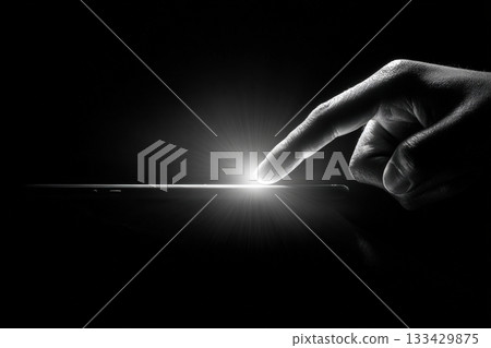 Minimalist Black-and-White Image of Hand Touching Glowing Smartphone 133429875