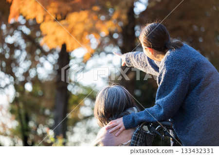 A faceless image of a caregiver and an elderly person outdoors in autumn. Image of an aging society and the end of life. Close-up of a person pointing. A faceless image of a caregiver and an elderly person outdoors in autumn. Image of an aging society and the end of life. Close-up of a person pointing. 133432331