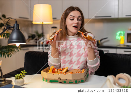 Adult woman eats pizza at night hungry cheat meal breaks diet enjoys secret late snack happy smiles Adult woman eats pizza at night hungry cheat meal breaks diet enjoys secret late snack happy smiles 133433818