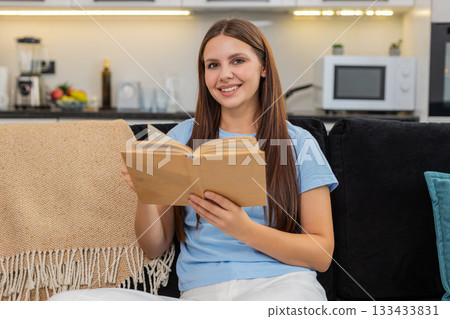 Young woman reads book enjoys leisure time smiles calm comfort simple weekend mood indoor rest joy Young woman reads book enjoys leisure time smiles calm comfort simple weekend mood indoor rest joy 133433831