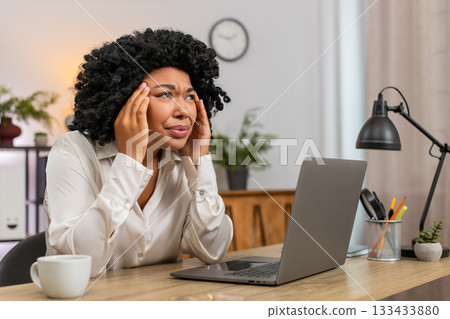 African American businesswoman massages temples suffering severe headache after long work strain day 133433880