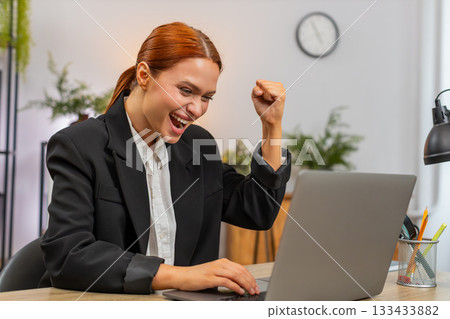 Young businesswoman celebrates project approval on laptop breathes loudly shouting victory success 133433882