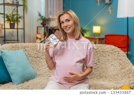 Pregnant woman tasting dark chocolate rolling eyes in delight rubbing belly enjoying sweet pleasure Pregnant woman tasting dark chocolate rolling eyes in delight rubbing belly enjoying sweet pleasure 133433887