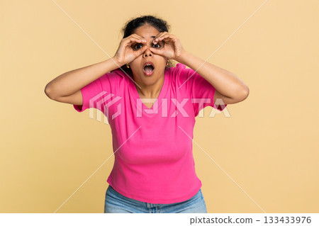 Indian woman playfully forming glasses with fingers, smiling cheerfully, humorously looking camera Indian woman playfully forming glasses with fingers, smiling cheerfully, humorously looking camera 133433976