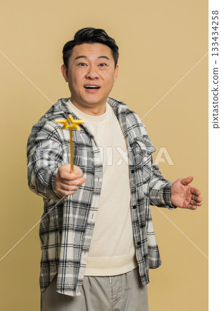 Magician witch Asian man gesturing with magic wand making wish come true, casting magician spell 133434258