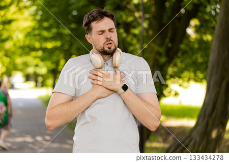 Sports man runner jogger having heart attack or chest pain after running workout in urban city park 133434278