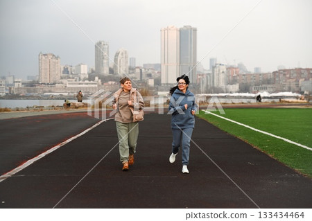 Two Russian women, aged 50 and 60, in tracksuits, run around a stadium in Vladivostok. Two Russian women, aged 50 and 60, in tracksuits, run around a stadium in Vladivostok. 133434464