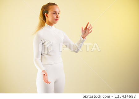 Woman in smartglasses gesturing against yellow background Woman in smartglasses gesturing against yellow background 133434688