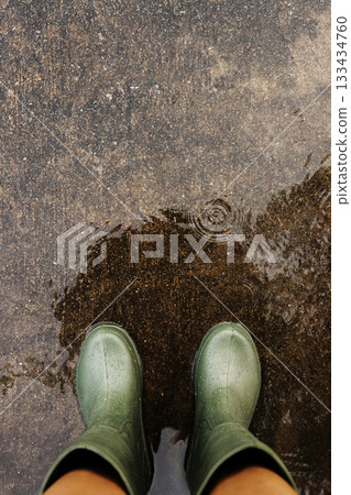 POV shot of person with rain boots standing on wet ground during rainfall, with raindrops in Rainy season POV shot of person with rain boots standing on wet ground during rainfall, with raindrops in Rainy season 133434760