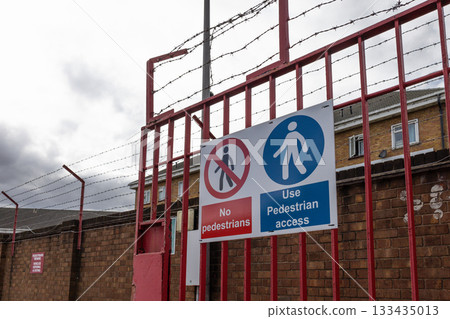 Industrial security gate with barbed wire and no entry safety signs 133435013