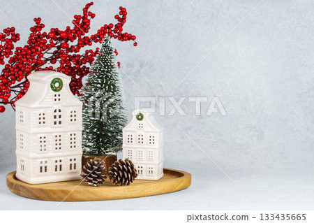Ceramic Christmas houses with pine Tree and winter decorations on wooden tray on white background Ceramic Christmas houses with pine Tree and winter decorations on wooden tray on white background 133435665