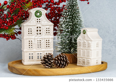 Ceramic Christmas houses with pine Tree and winter decorations on wooden tray on white background 133435666