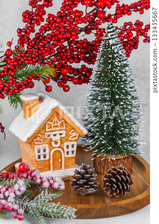 Gingerbread style ceramic Christmas house with ornaments, holly berries and snowy spruce tree Gingerbread style ceramic Christmas house with ornaments, holly berries and snowy spruce tree 133435667