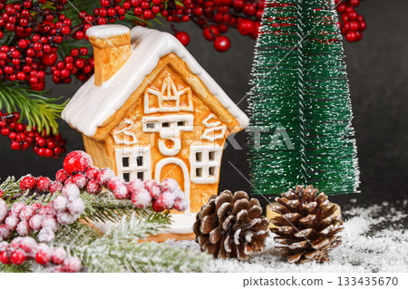 Gingerbread style ceramic Christmas house with pine cone, holly berries and snowy winter tree Gingerbread style ceramic Christmas house with pine cone, holly berries and snowy winter tree 133435670