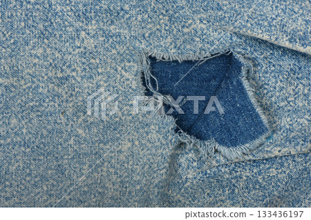 Ripped blue hipster jeans material. Destroyed denim Cloth texture. Close up. Ripped blue hipster jeans material. Destroyed denim Cloth texture. Close up. 133436197