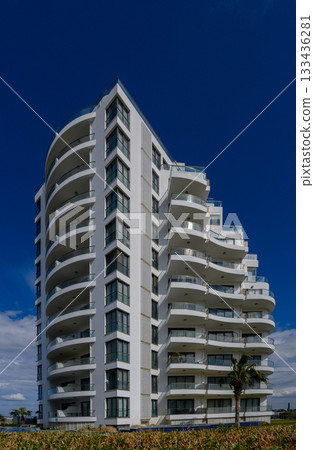 Modern architecture stands tall against a vibrant blue sky showcasing elegant curves and balconies Modern architecture stands tall against a vibrant blue sky showcasing elegant curves and balconies 133436281