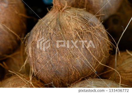 Natural beauty of brown spherical coconut shells displayed in a vibrant market setting 133436772