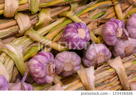 Garlic bunches displayed vibrantly at a bustling farmer's market in early autumn 133436886