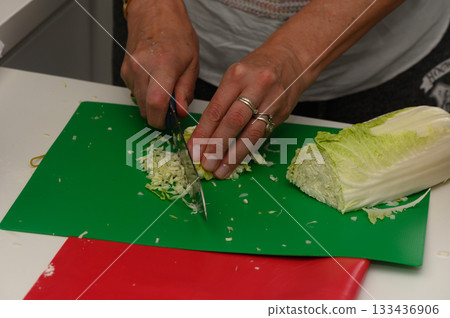 Chopping fresh cabbage in a cozy kitchen while preparing a healthy meal at home late in the afternoon Chopping fresh cabbage in a cozy kitchen while preparing a healthy meal at home late in the afternoon 133436906
