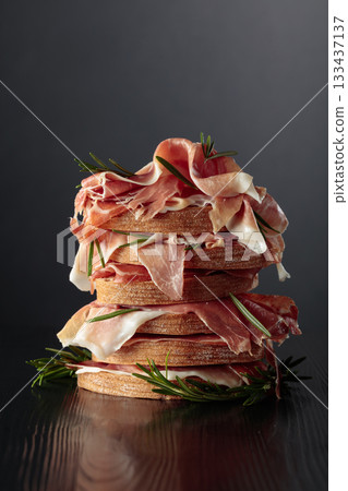 Italian prosciutto or Spanish jamon with bread and rosemary. Italian prosciutto or Spanish jamon with bread and rosemary. 133437137