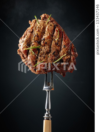 Grilled beef steak on a fork. Grilled beef steak on a fork. 133437146