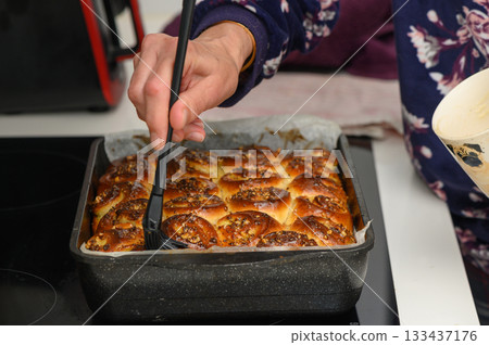 Baking sweet rolls in a cozy kitchen, a delightful moment filled with warmth and delicious aromas during a chilly evening Baking sweet rolls in a cozy kitchen, a delightful moment filled with warmth and delicious aromas during a chilly evening 133437176